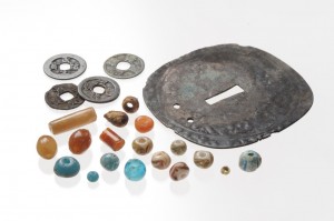 トンボ玉や古銭や和鏡を鍔の形を模して加工した装飾品の写真